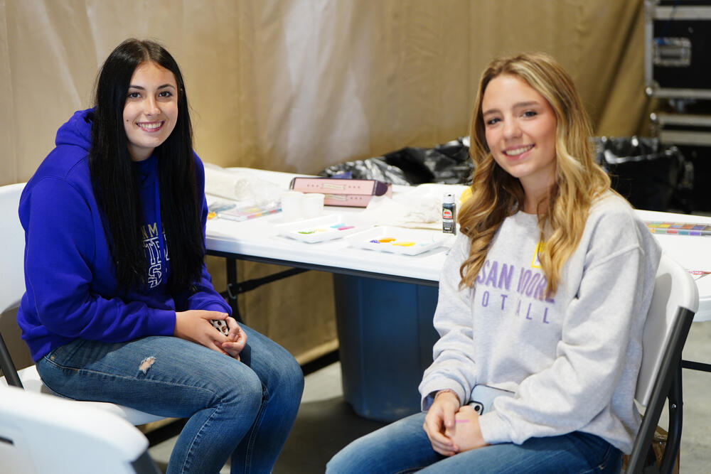 Two female volunteers at the face painting booth during the exceptional needs rodeo.