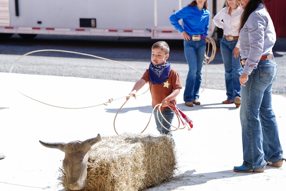 A young boy throwing a rope over a fake steer at a roping game. 