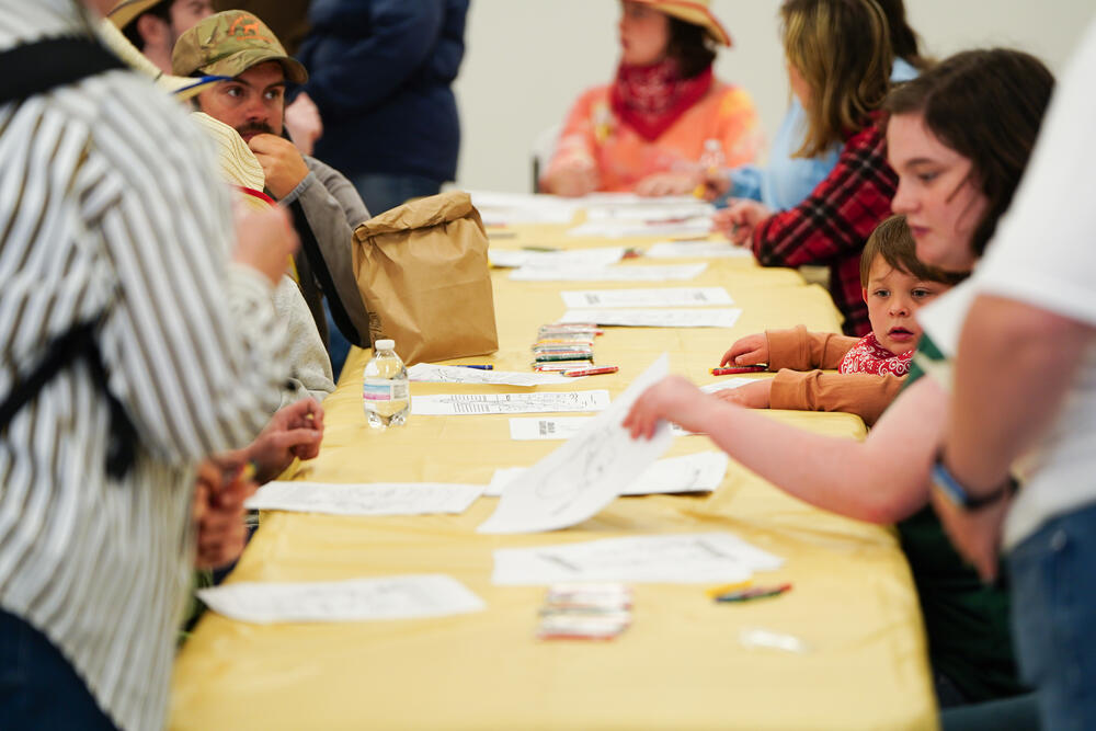 A groung of kids coloring at a table. 